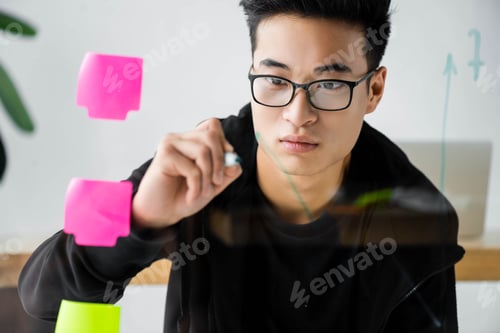 Preview: asian seo manager in glasses painting arrow on glass