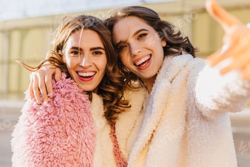 Preview: Interested curly woman making selfie with best friend in autumn day. Adorable brown-haired girl in