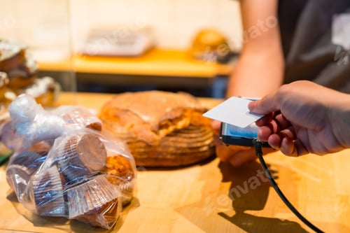 Preview: Customer in the bakery shop buying an bread from the baker in the workshop, paying with the card