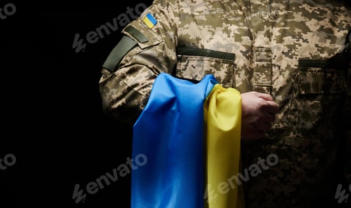 Preview: Ukrainian soldier holds a flag of the independent state of Ukraine. Steadfastness and courage
