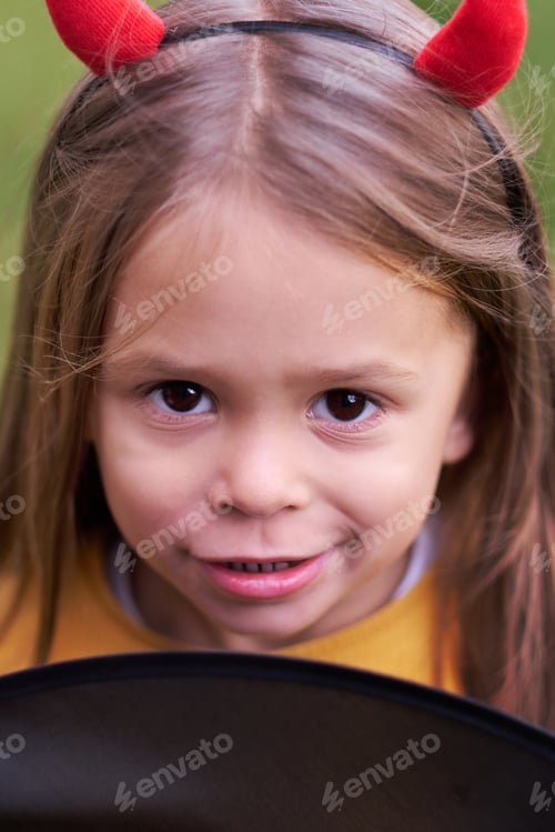 Preview: Portrait of girl in a Halloween devil costume with horns. Happy childhood. All Saints Day.