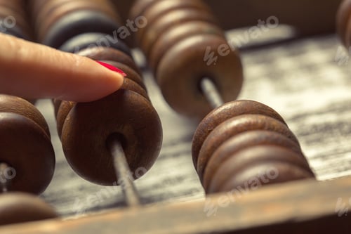 Vista previa: Close-up view of a finger touching a wooden bead on a traditional abacus in bright light