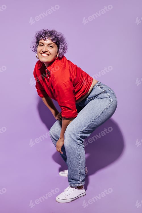 Preview: Smiling mischievous woman with curly hair in stylish bright clothes and white shoes posing on camer