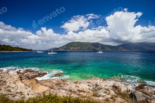 Preview: Crystal clear transparent blue turquoise teal Mediterranean sea water in Fiskardo town. White yacht