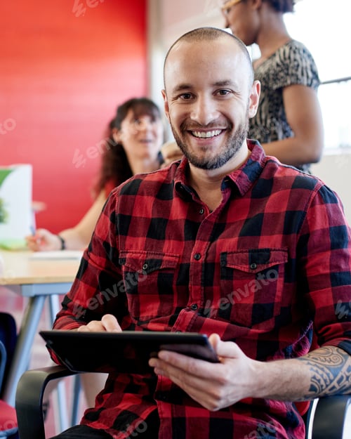 Preview: Confident male designer working on a digital tablet in red creative office space