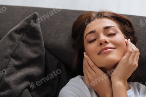 Preview: top view of attractive woman dreaming while resting on sofa in living room