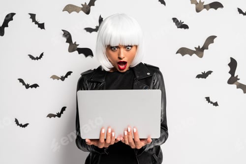 Preview: shocked woman in white wig holding laptop in Halloween