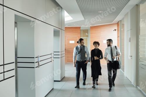 Preview: Three young cheerful colleagues in formalwear chatting on their way to office