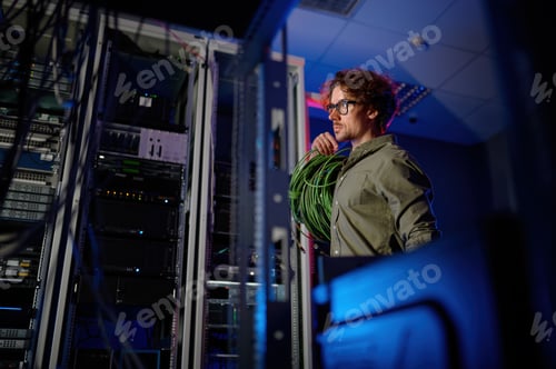 Preview: Data center engineer with many optic wires cables walking next to computer racks
