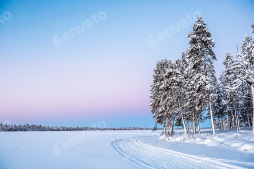 Preview: Frozen snow covered lake in the winter landscape in Lapland at sunset inside the Arctic Circle in Fi