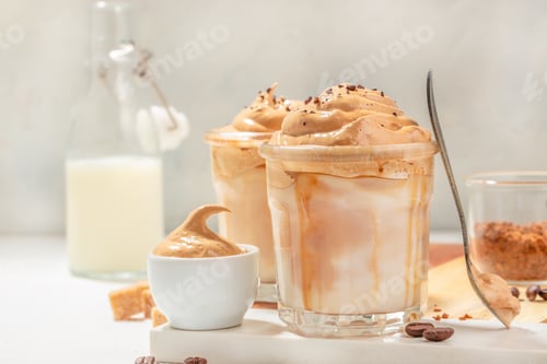 Preview: Dalgona cream coffee whipping on cold milk In a transparent glass on light background