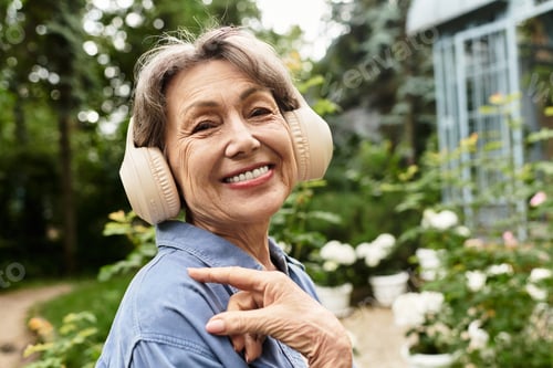 Preview: Joyful senior woman enjoying her time in a vibrant garden filled with blooms and greenery