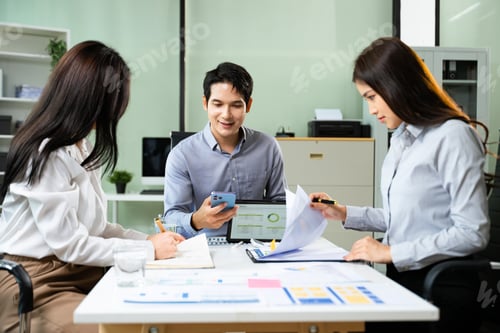 Preview: Young business professionals working together in modern office, using tablet and notebooks