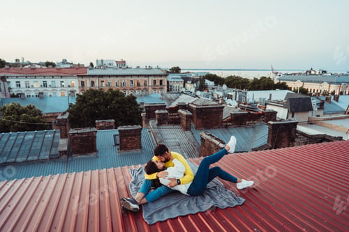 Preview: Loving young couple is sitting on the roof of the house