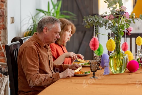 Preview: Grandpa and grandma eating at Easter dinner sitting at the table at home