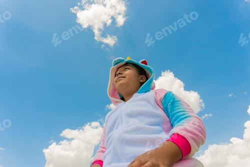 Preview: Closeup shot of a happy Hispanic boy in a unicorn costume and blue sky on the background