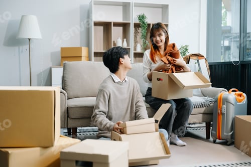 Preview: Happy asian young attractive couple man and woman with big boxes moving into a new house,