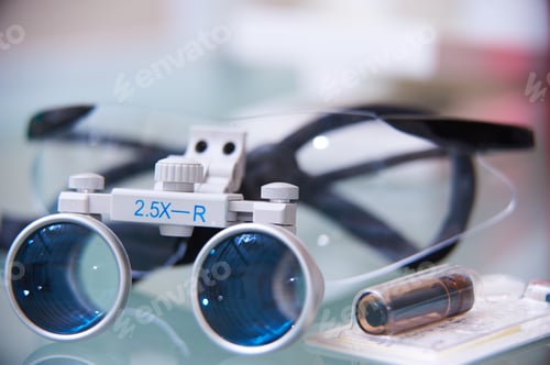 Preview: Close-up of dental or surgical loupes with magnifying lenses on a reflective surface. Professional