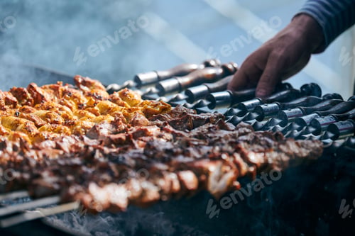 Preview: Cooking pork barbecue with skewers cubes of meat on BBQ grill, traditional Central Asia dish