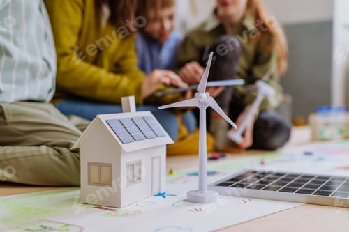 Preview: Close-up of house model with solar system and wind turbine during a school lesson.
