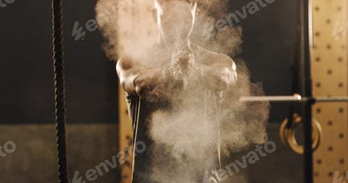 Preview: Shot of a muscular young man clapping his hands dusted with sports chalk in a gym