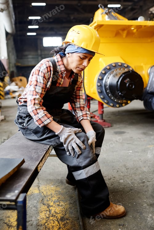 Preview: Young female engineer touching her injured knee after accident at work