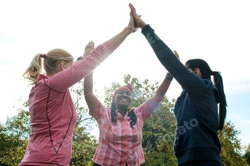 Preview: Three fitness mature woman doing high five in a park.