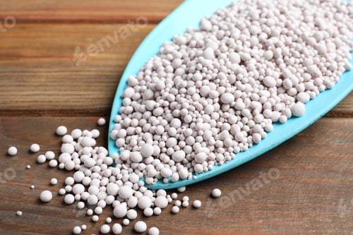 Preview: Chemical fertilizer in metal gardening shovel on wooden table, closeup