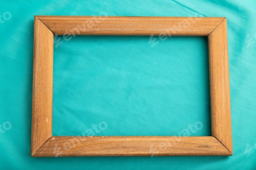 Preview: Wooden frame on smooth silk blue tissue. Top view, natural textile background.