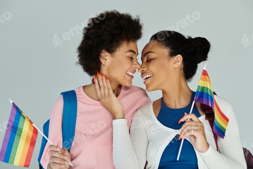 Preview: Joyful celebration of love between two friends holding rainbow flags in a cozy indoor setting