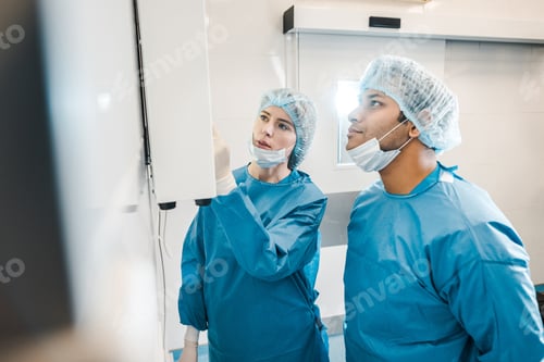 Preview: good-looking and beautiful doctors in uniforms and medical masks looking at screen