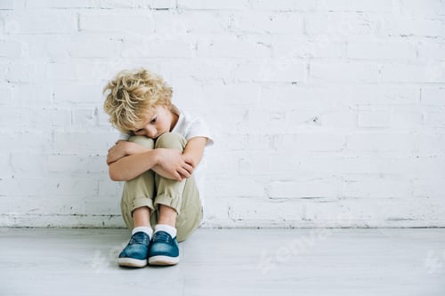 Preview: upset preteen boy sitting on floor at home