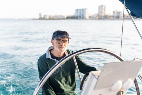 Preview: Senior skipper steering sailboat on sunny day in ocean