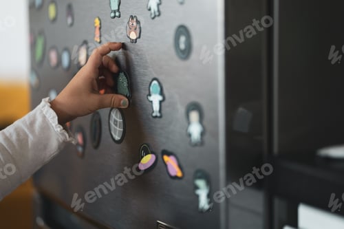 Preview: Child Attaching Magnet to Silver Refrigerator Door