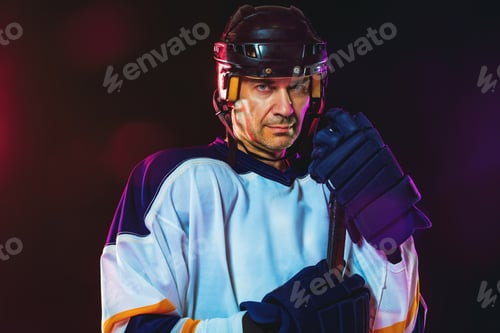 Preview: Male hockey player with the stick on ice court and dark neon colored background