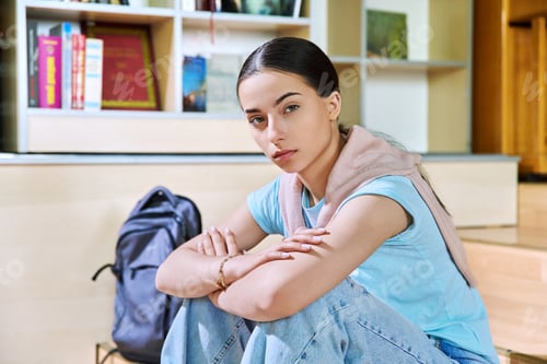 Preview: Serious teenage girl high school student sitting in class looking at camera