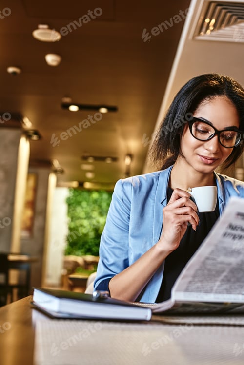 Preview: African american businesswoman is reading a newspaper while resting in the cafe