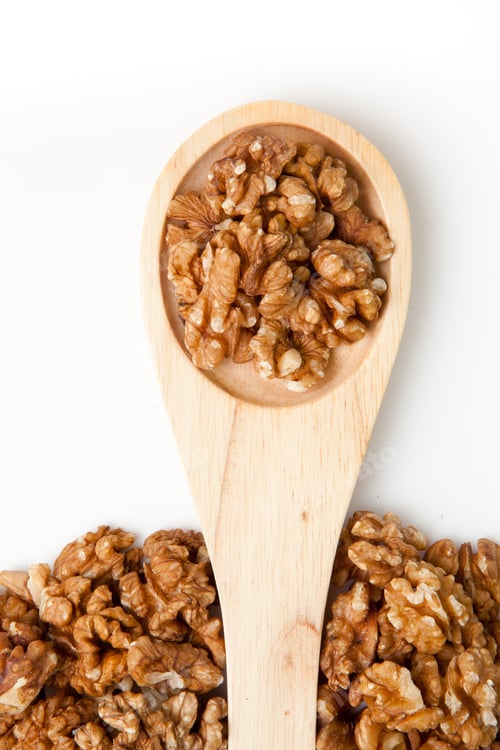 Preview: Wooden spoon with nuts against a white background