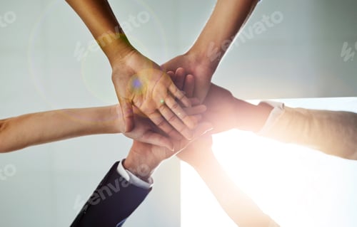 Preview: Low angle shot of a group of colleagues joining their hands in solidarity