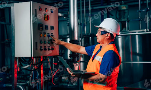 Preview: Engineering man in protective safety uniform working with clipboard at factory.