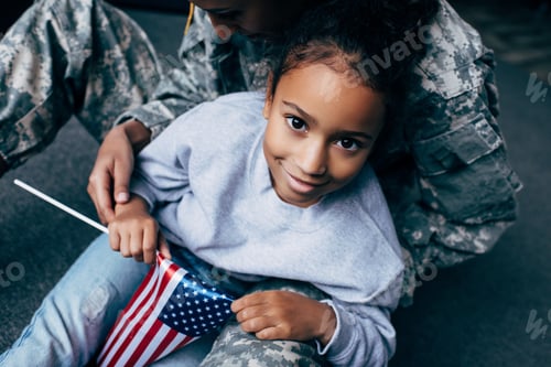 Preview: african american daughter and female soldier in military uniform with american flag at home