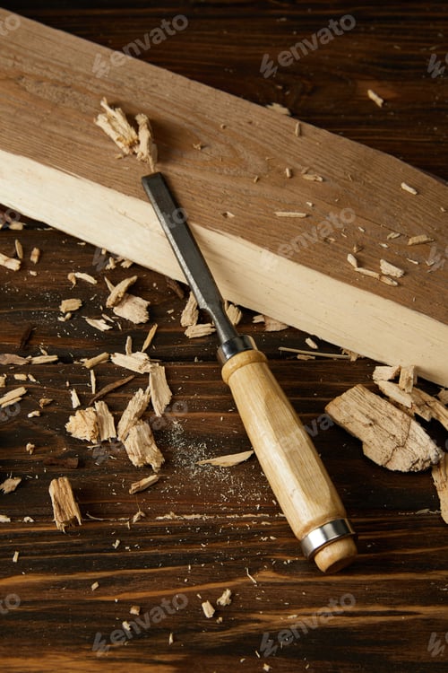 Preview: close up view of chisel and wooden pieces on brown table