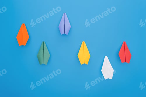 Preview: Flat lay with colorful paper planes on blue surface