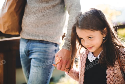 Preview: A small girl with unrecognizable father walking outdoors in park in autumn.