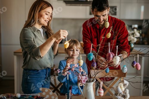 Preview: Family decorating branches with colorful easter eggs at home