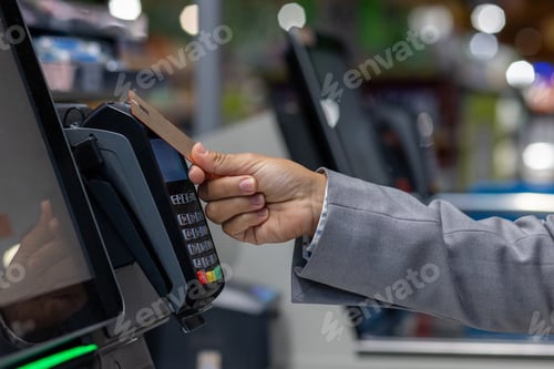 Preview: Close-up photo of the hand of a female buyer paying in a supermarket store with a bank credit card