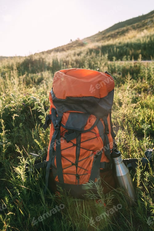 Preview: Backpack and thermos flask on a meadow