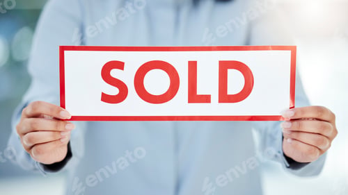 Sold Sign Held by Person in Blue Shirt