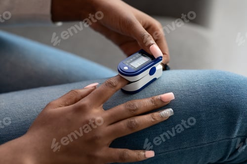 Preview: Unrecognizable Black Woman Using Pulse Oximeter Clip Machine On Finger At Home