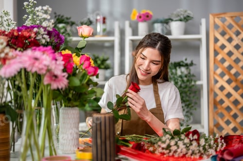 Preview: Asian young florist girl completing beautiful bouquet in flower shop.